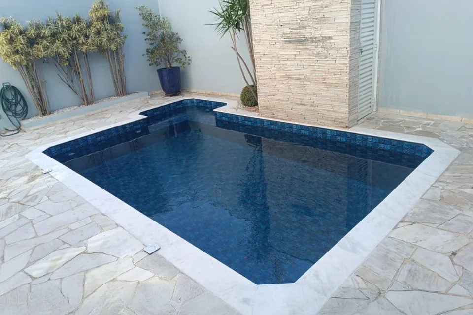 Piscina residencial revestida em azul ao lado do jardim