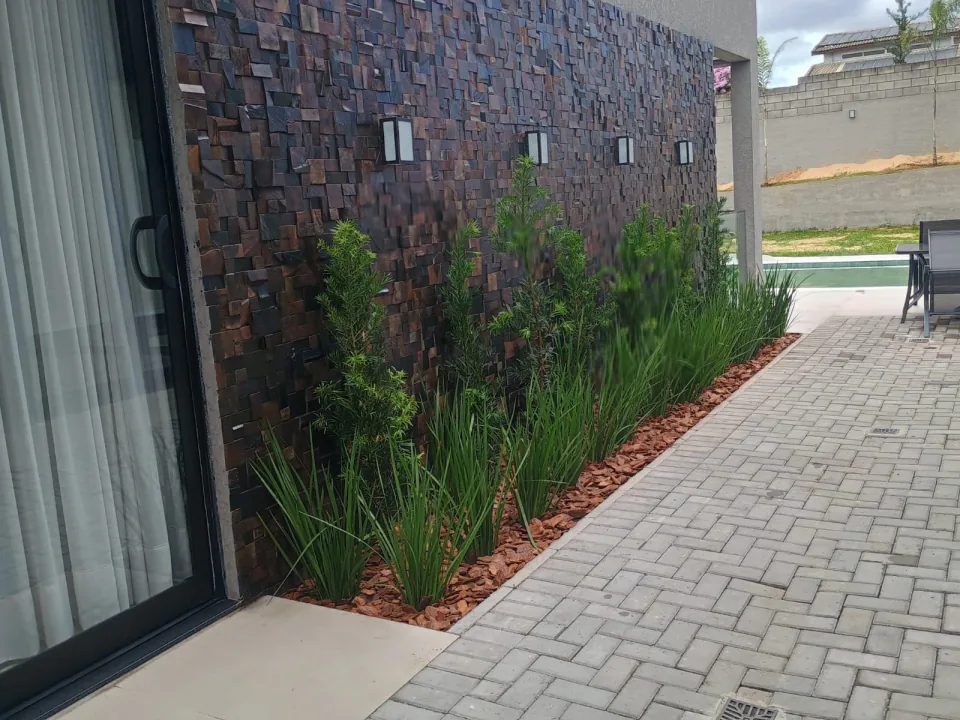 Jardim linear junto a muro de pedra em residência