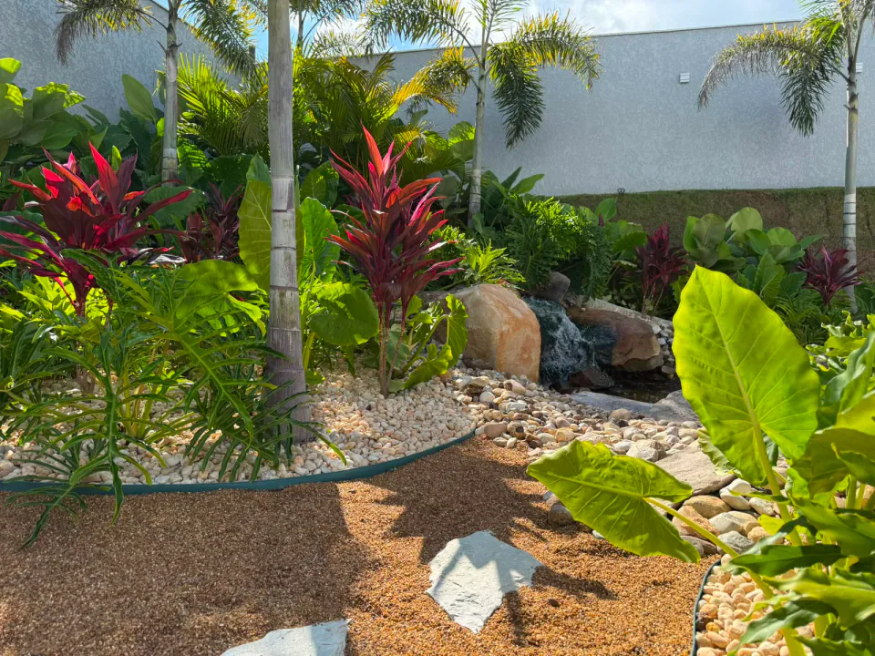 Jardim tropical com cascata, pedras e caminho gramado