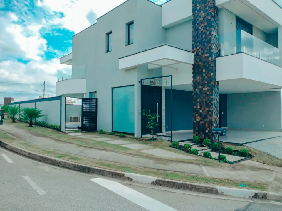 Paisagismo em fachada residencial com folhagens e pedras