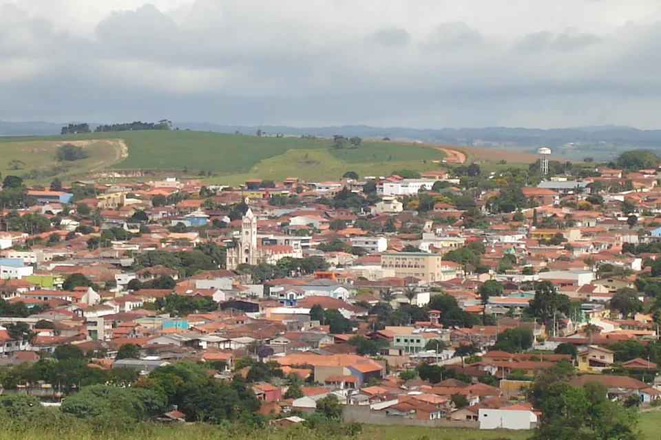 Vista do centro de São Miguel Arcanjo, São Paulo, com a igreja entre os telhados e colinas ao fundo.