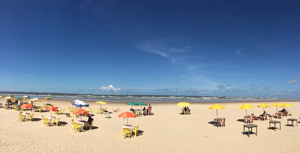 Praia de Atalaia em Aracaju, Sergipe, com faixa de areia, guarda-sóis e mar.