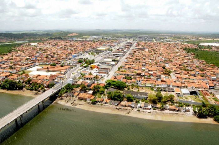 Vista aérea do conjunto João Alves, em Nossa Senhora do Socorro, Sergipe, com casas, ruas e ponte.