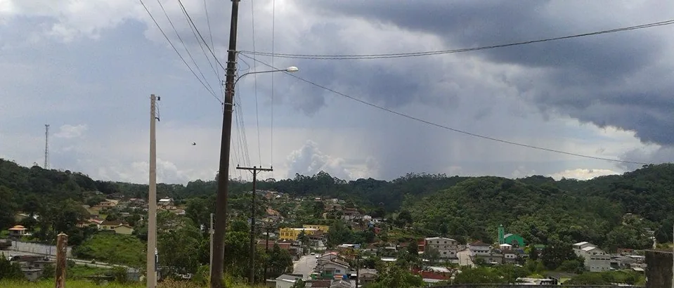Vista de Tapiraí, São Paulo, com casas, uma igreja e morros arborizados.