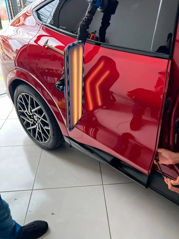 Detalhe de porta de automóvel vermelho durante trabalho na carroceria