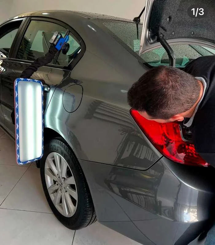 Profissional trabalhando na lateral de um automóvel cinza