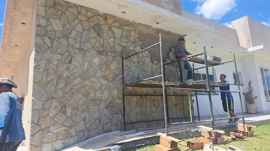 Aplicação de revestimento de pedra em fachada com andaime