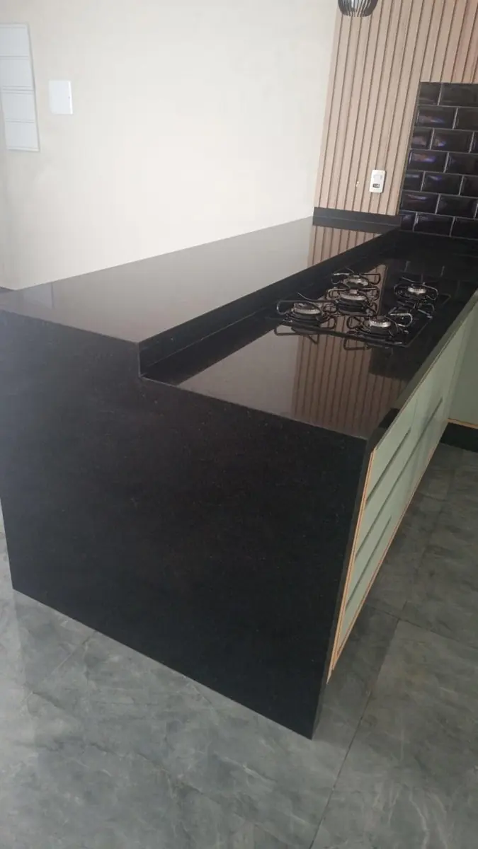 Bancada escura com cooktop e fechamento lateral até o piso