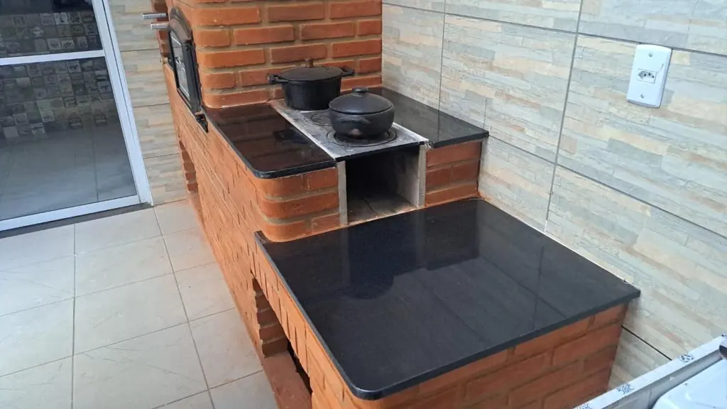 Bancadas escuras junto a uma churrasqueira de tijolos