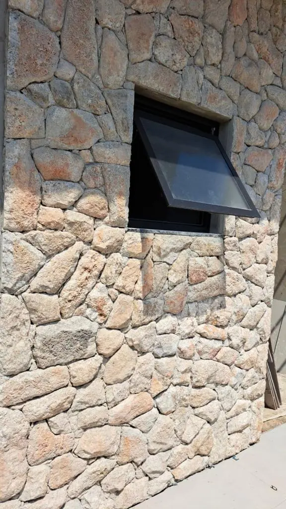 Detalhe de revestimento em pedras irregulares ao redor de uma janela